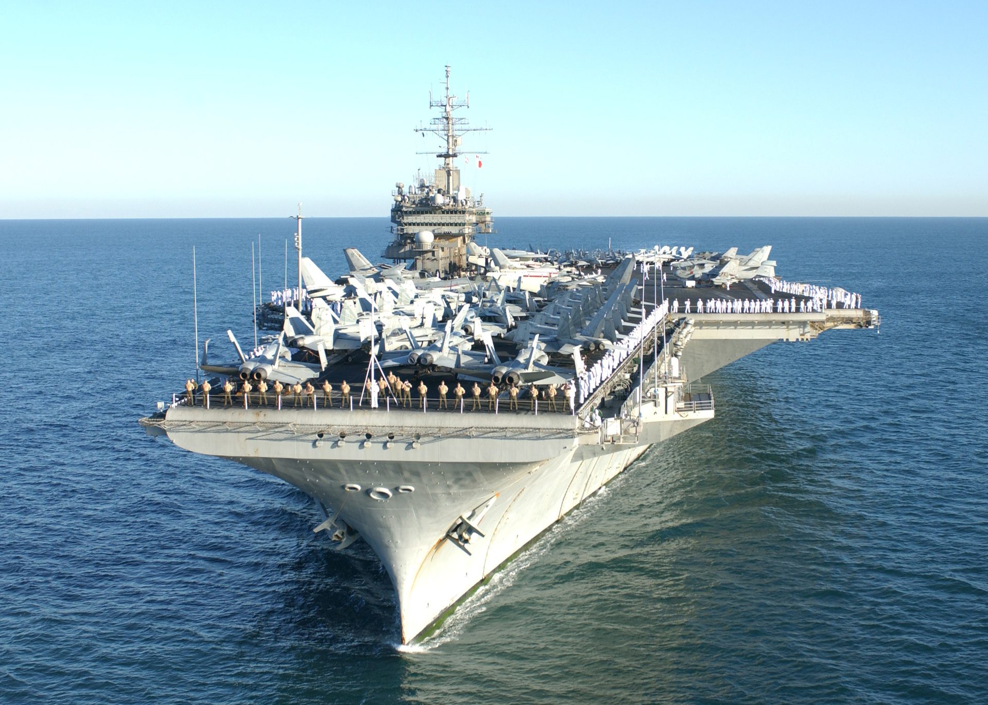 USS Constellation (CV-64) at sea with the crew manning the rails